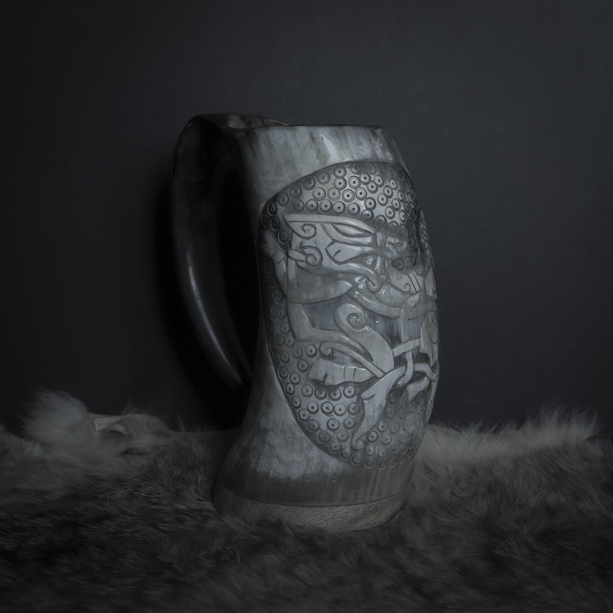 Handsnidad hornmugg med organiskt horn, relief-snidad med norskt mytologiska motiv: Tyr-ansikte, Fenrir-varg och detaljerade skalsmönster med runiska markeringar.