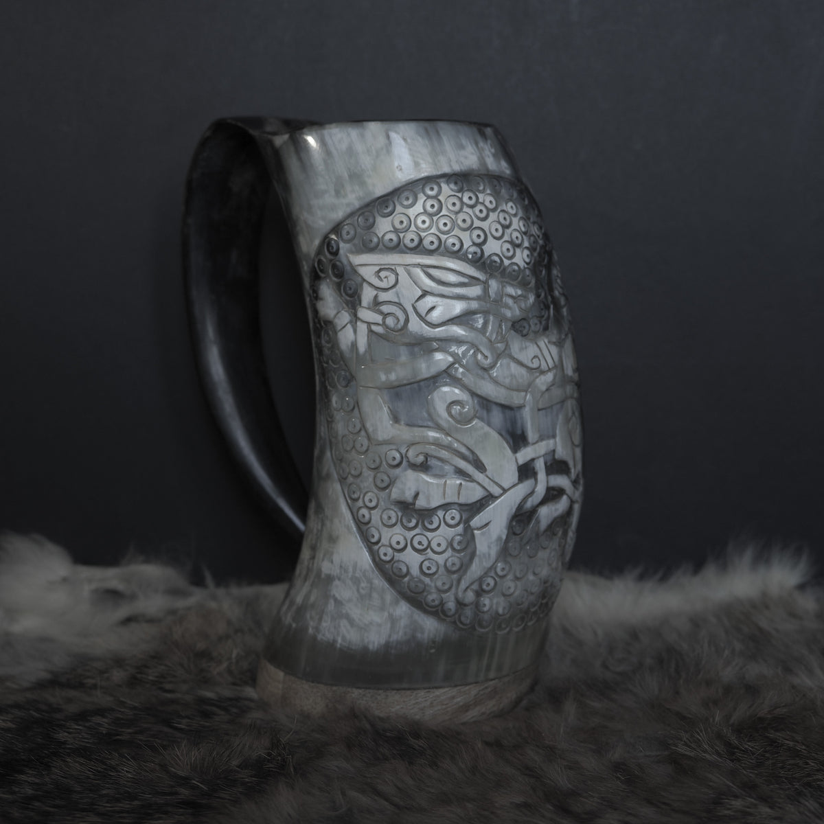 Handsnidad hornmugg i organiskt horn, från frågamål visad med relief-snidningar av norskt gudar Tyr och vargungen Fenrir med detaljerade runiska mönster på brun-svart horn.