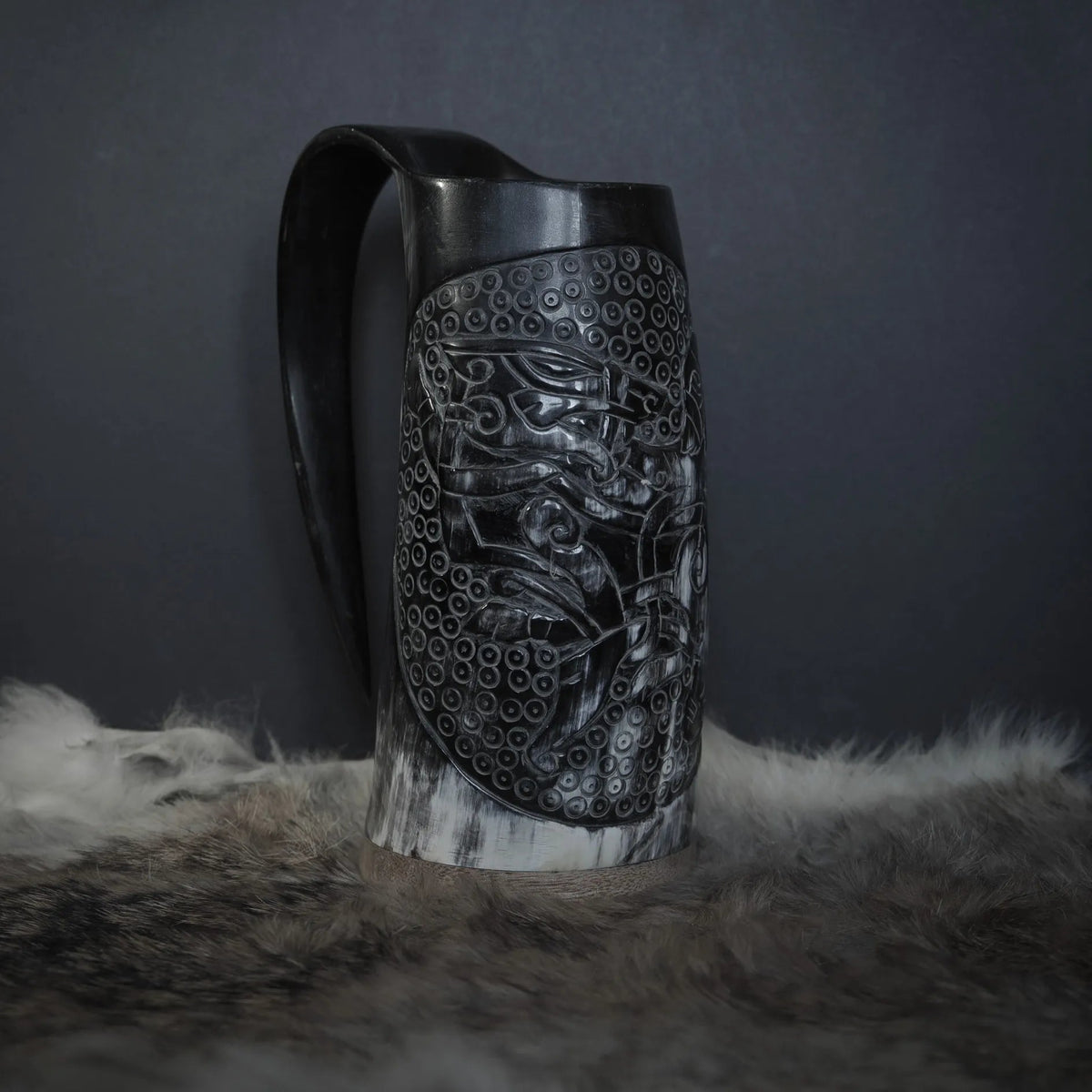 Hornmugg från framsidan med handsnidad Tyr och Fenris mytologi omgiven av precis prickmönster. Naturlig horn färg med synliga växtringar. Svart handtag.