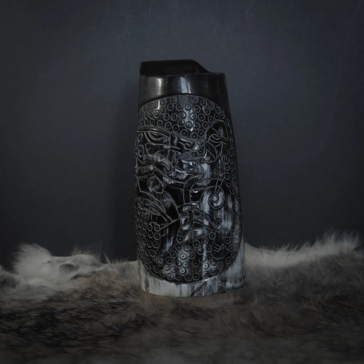 Framansicht av hornmugg med handsnidad Tyr och Fenris motif. Naturhorn med svart handtag. Studio-fotograferad på neutral bakgrund.