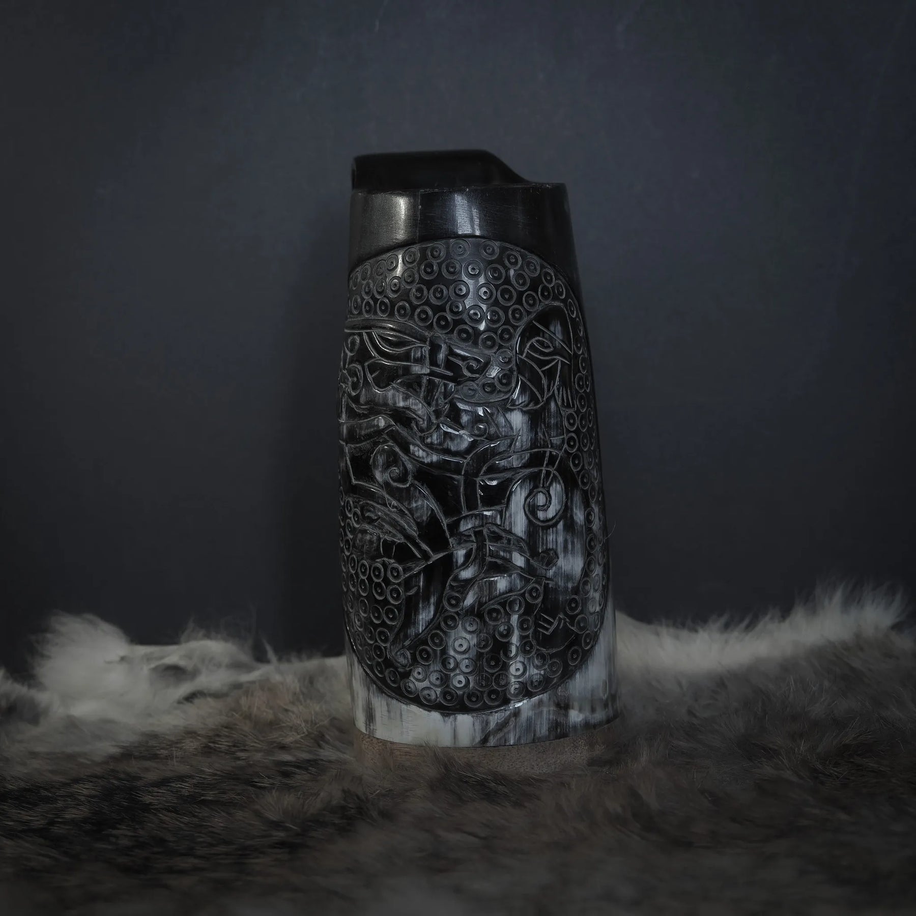 Framansicht av hornmugg med handsnidad Tyr och Fenris motif. Naturhorn med svart handtag. Studio-fotograferad på neutral bakgrund.
