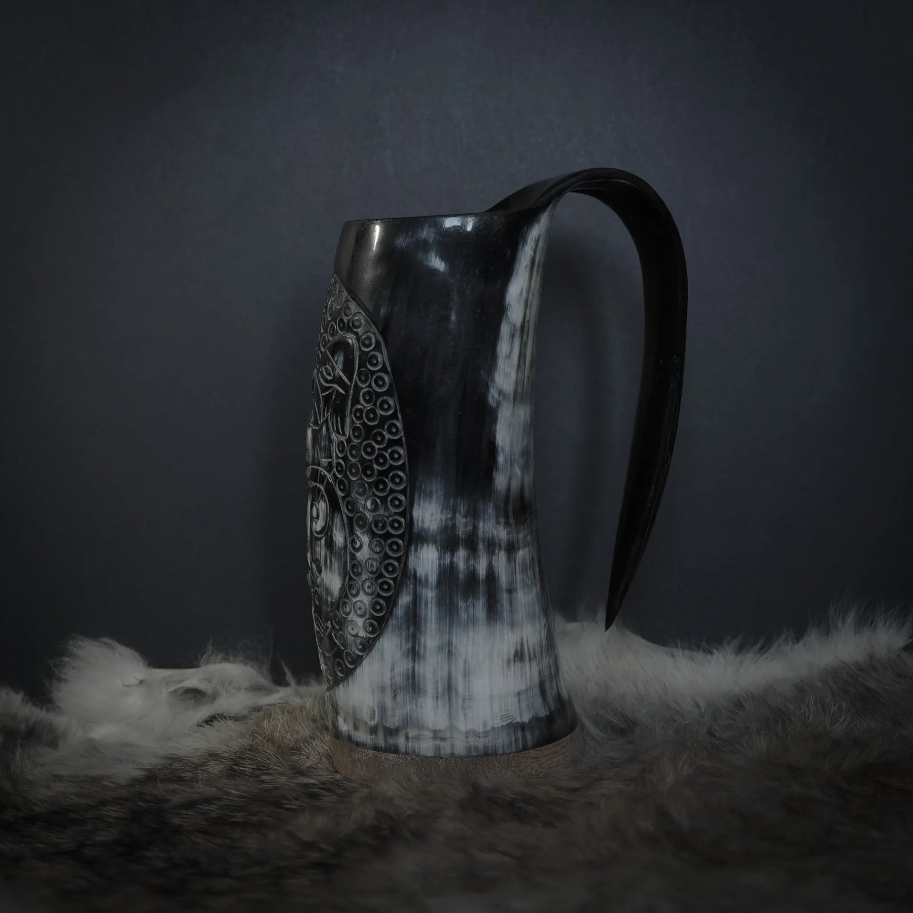 Hornmugg från sidan visar svart handtag och hornets naturliga struktur. Snidad Tyr och Fenris motiv synlig. Studio belysning.