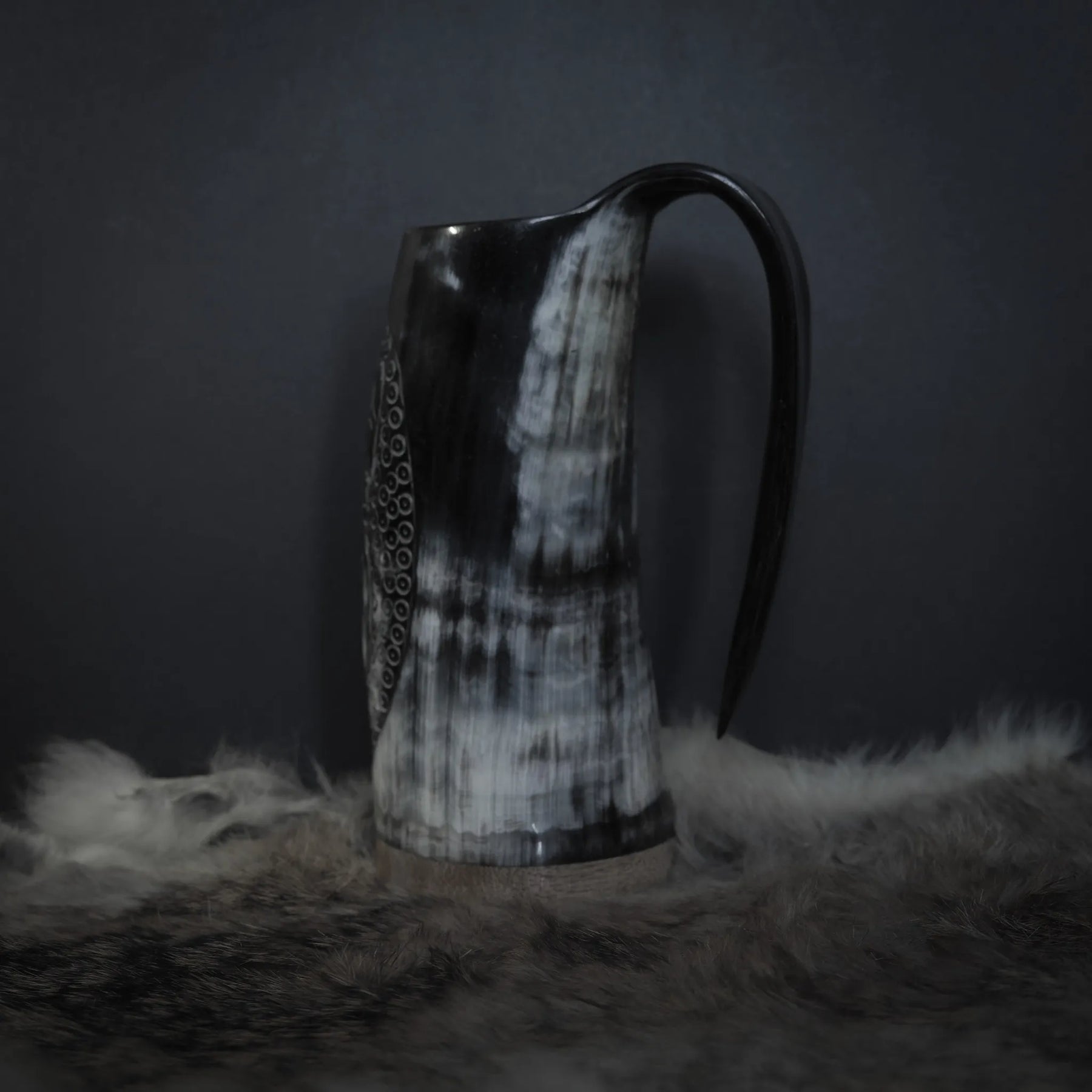 Hornmugg från baksidan visar svart handtag och delvis syn av Tyr och Fenris sniderier. Naturhorn med patina.