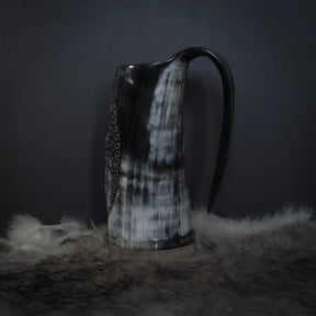 Hornmugg från baksidan visar svart handtag och delvis syn av Tyr och Fenris sniderier. Naturhorn med patina.