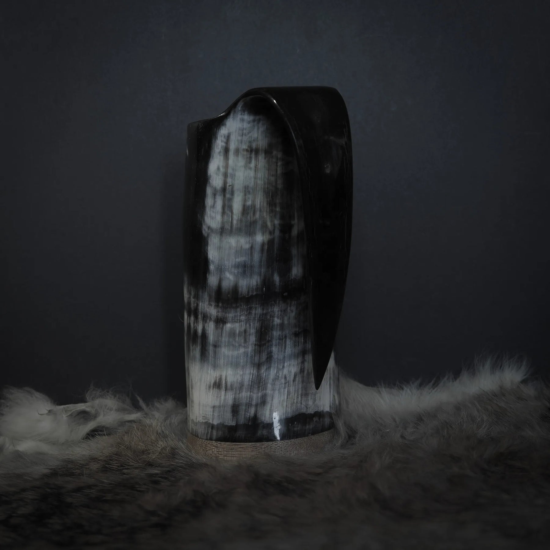 Hornmugg från tre-fjärdedels baksidvinkel. Svart handtag. Delvis syn av Tyr och Fenris sniderier med prickmönster.