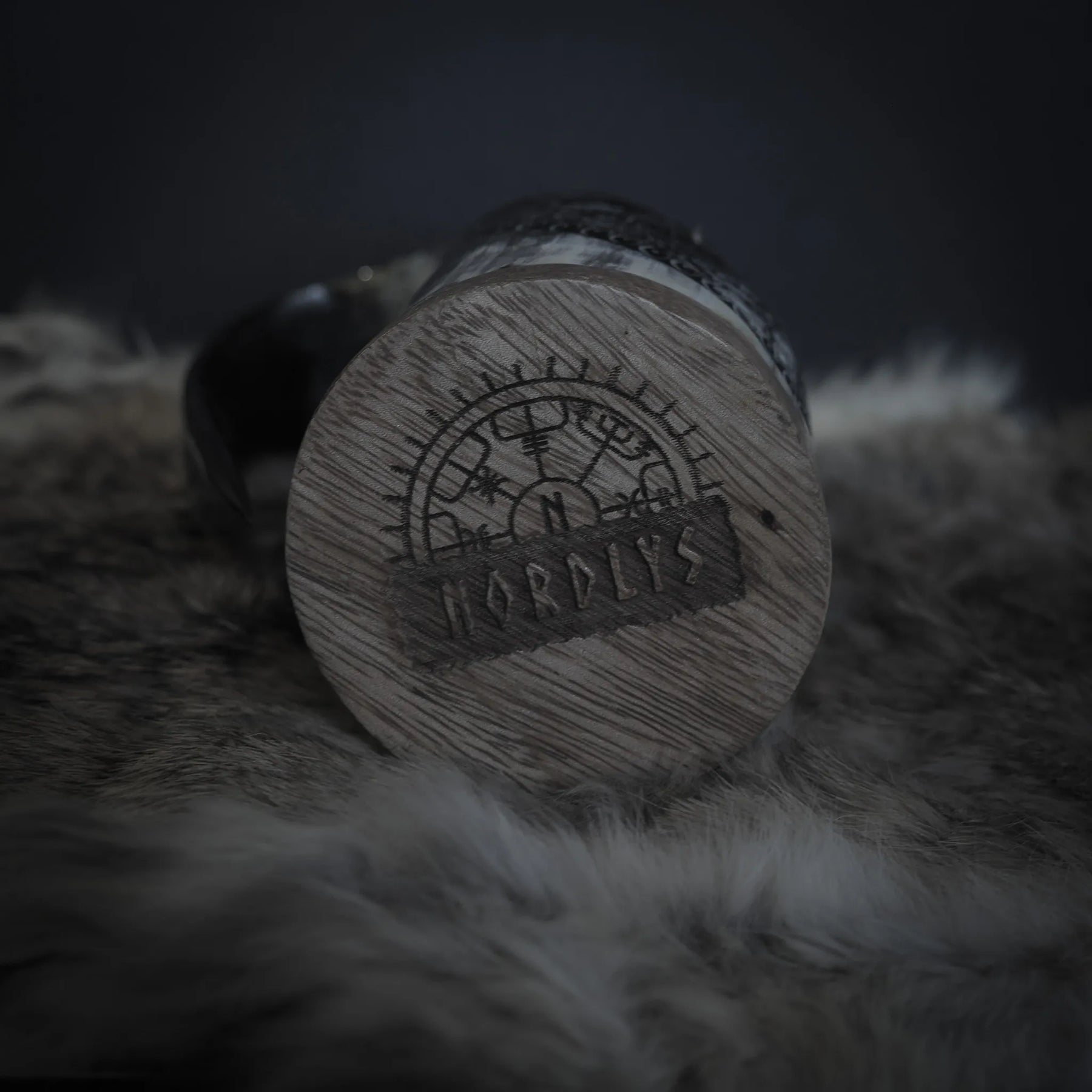 Detaljnärbild av hornmuggans mästarmark med Nordiska runor och cirkulär förseglingssymbol på botten. Makrofotografi visar snidningarnas djup.