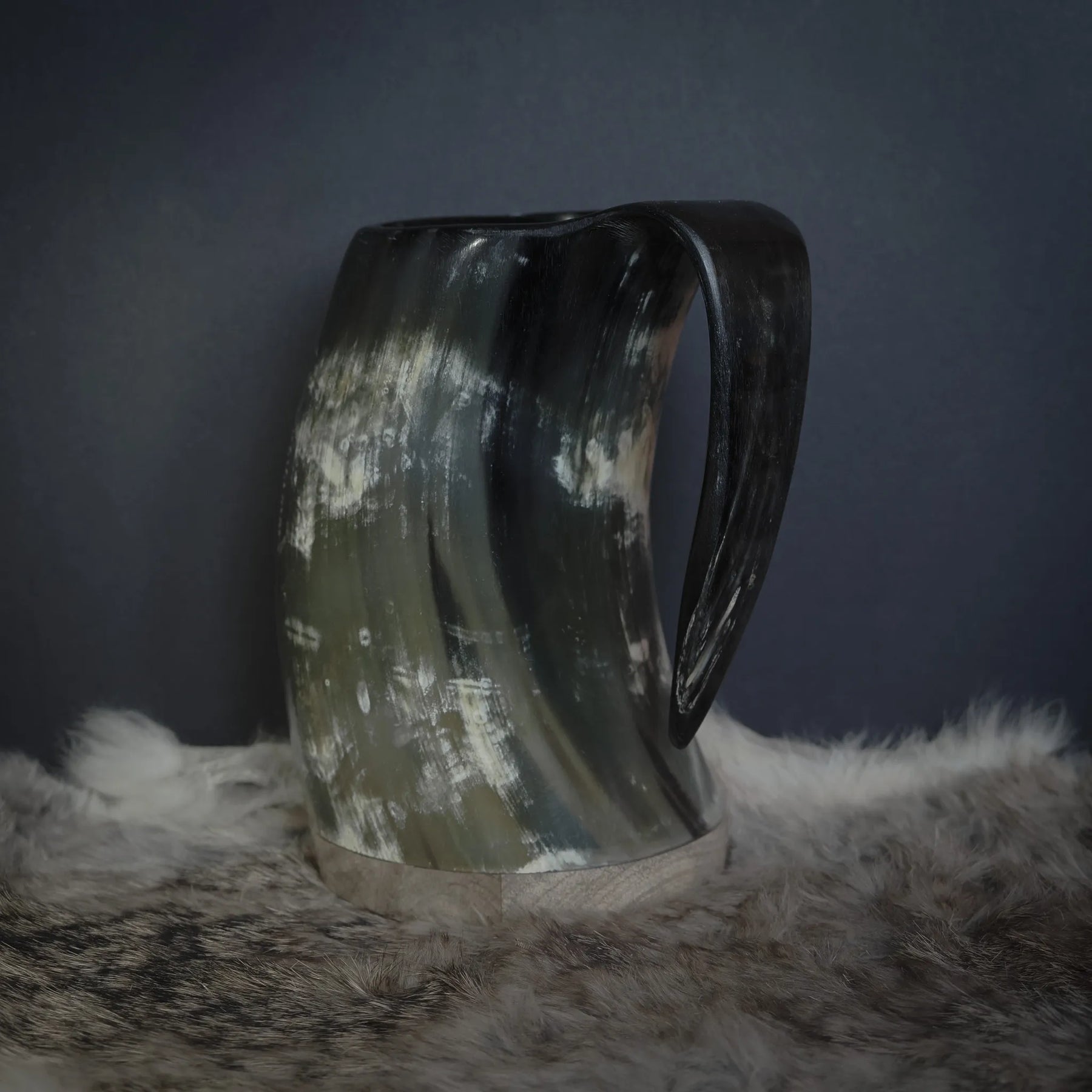 Hornmugg fotograferad från handtagssidan. Stor ergonomisk handtag skuret från samma naturliga material. Horn visar naturlig ljus-mörkmarkering och kornstruktur från sidan.