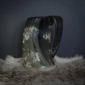 Hornmugg fotograferad från handtagssidan. Stor ergonomisk handtag skuret från samma naturliga material. Horn visar naturlig ljus-mörkmarkering och kornstruktur från sidan.