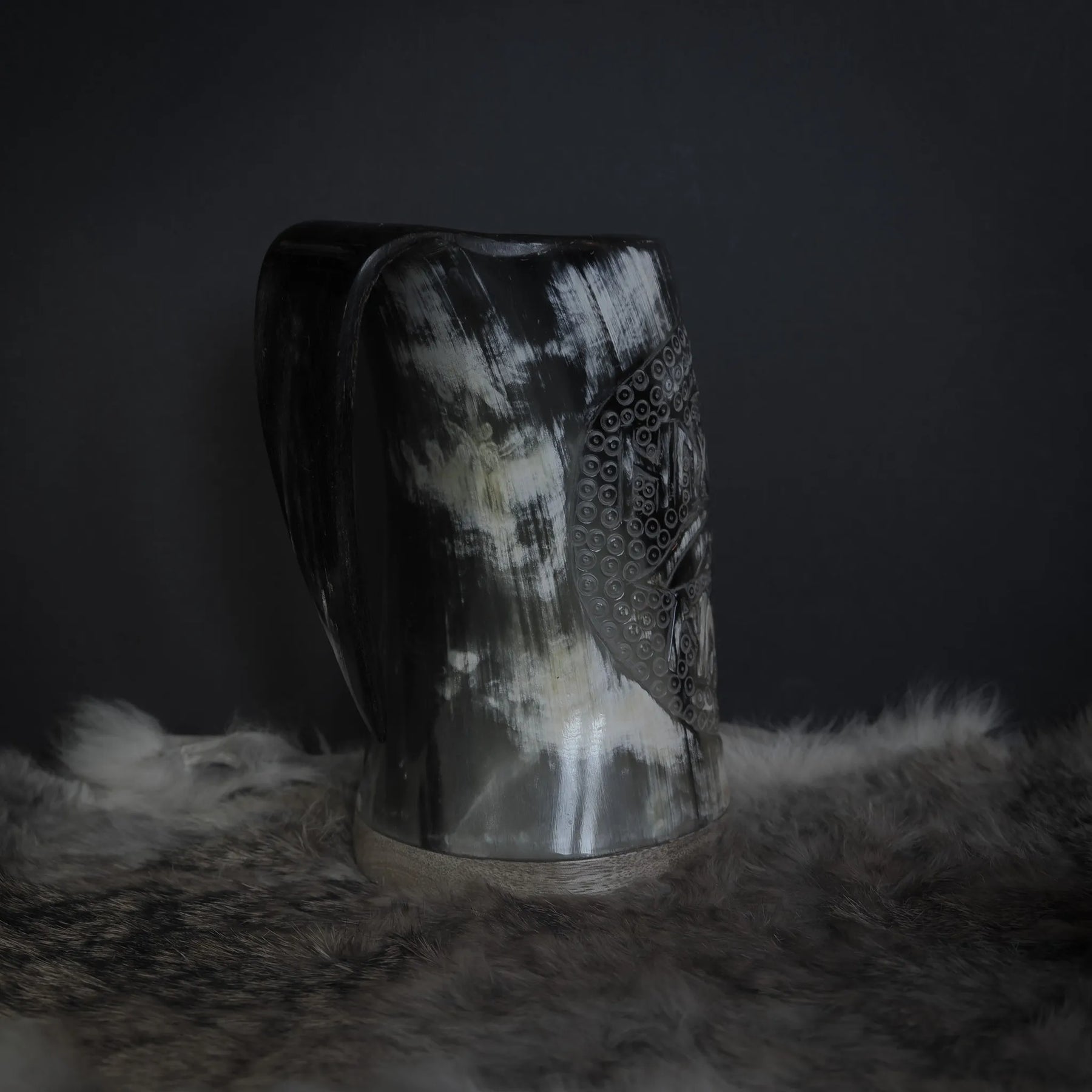 Handsnidad hornmugg med både Hugin och Munin-korpar karvade i ett band. Detaljer visar båda fåglarnas fjädrar och ett omfattande prickmönster. Naturlig horn med handtag väl synligt från denna vinkel.