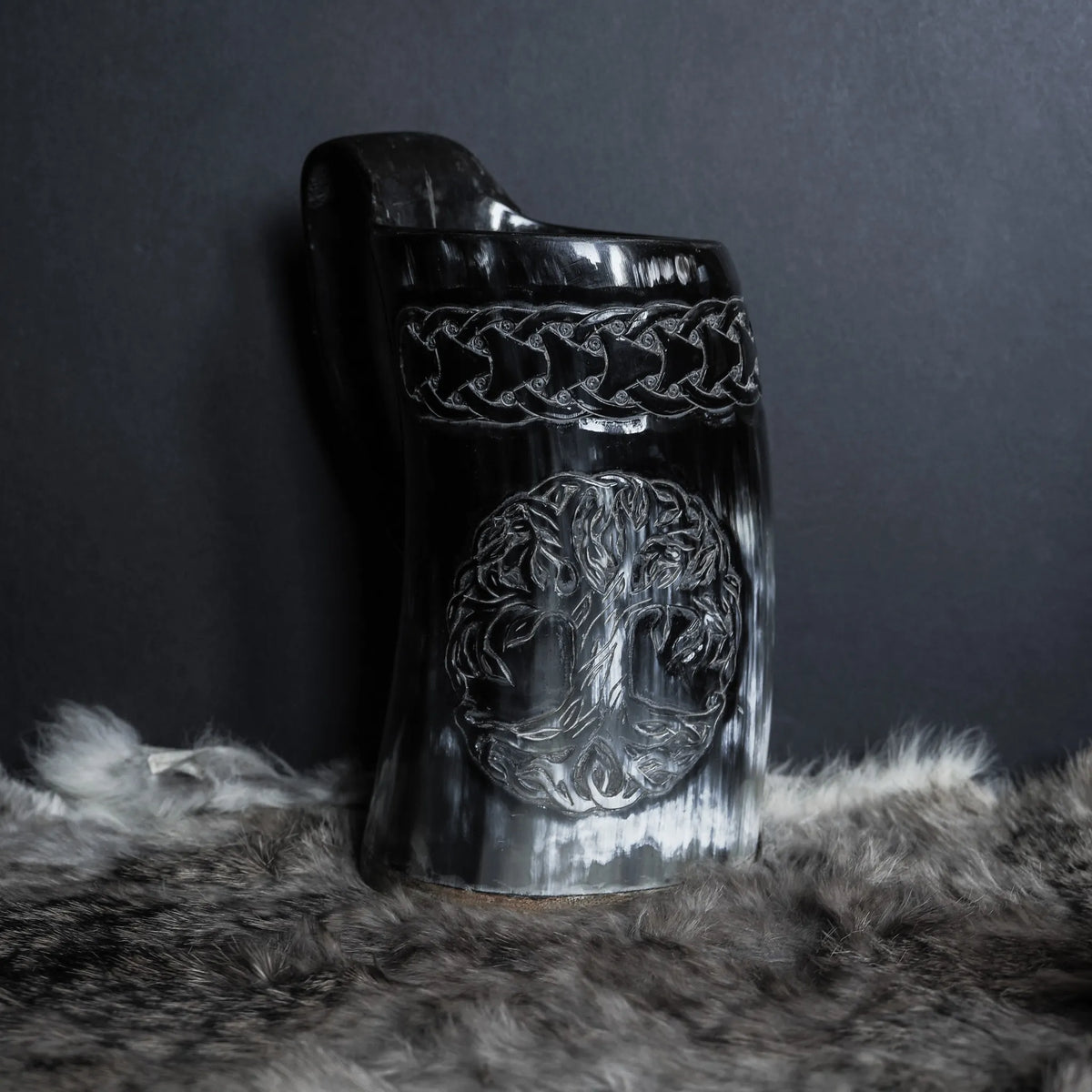 Hornmugg från framsidan med Livets träd-motiv och keltisk knutöversättning. Svart polerad horn med präglad Vikingatextur. Stor båge-formad handtag synligt.