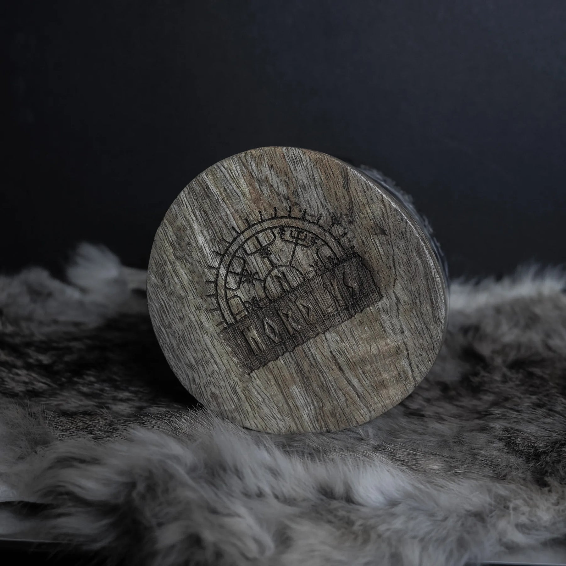 Handsnidad hornmugg sedd från ovan med Livets träds-motiv. Trädets grenar slingrar sig i cirkulära mönster. Naturligt hornmaterial med fin kornstruktur framhävd mot mörk bakgrund och vit päls.