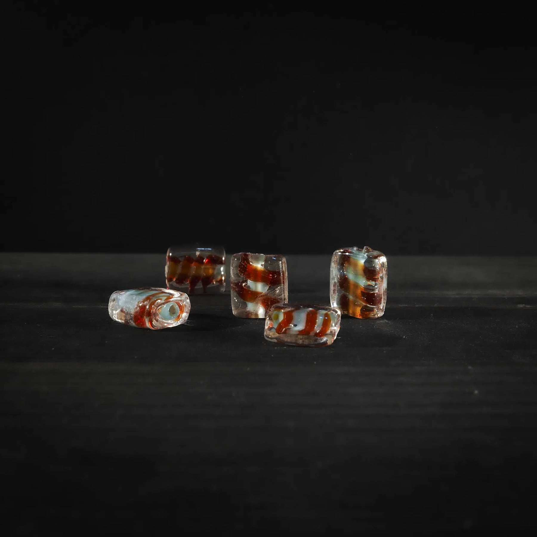 Angular glass bead with red spiral detail. Faceted design in transparent glass with red spiral running through each bead. 2mm hole for threading. Suitable for jewelry making and crafts.