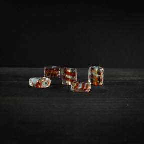 Angular glass bead with red spiral detail. Faceted design in transparent glass with red spiral running through each bead. 2mm hole for threading. Suitable for jewelry making and crafts.