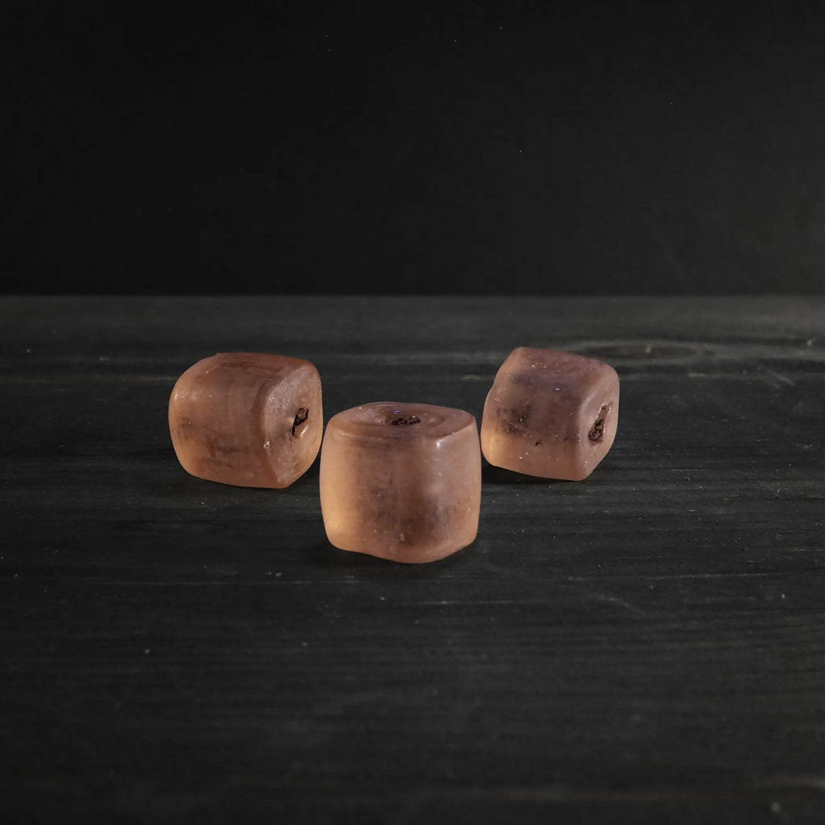 En persikafärgad transparent glaspärla med cylindrisk form