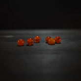 Rund orange pärla - Round orange glass beads (6mm) on dark wood. Warm translucent amber glass beads for jewelry and craft applications.