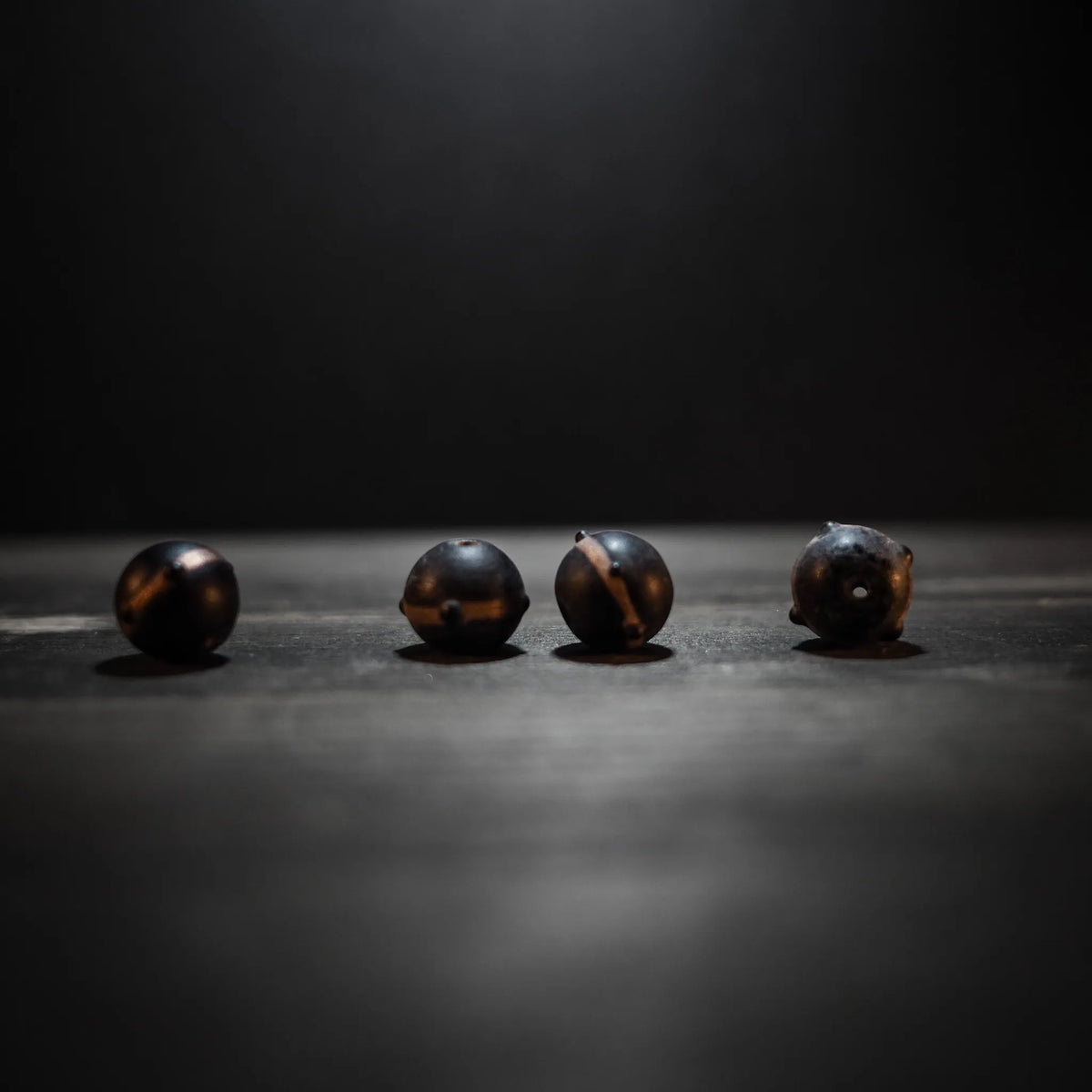 Svart pärla med guldfärg och metallisk glans. 12mm genomål med 1mm hål. Vikingainspirerad glaspärla med koppar- och brons-ränder.