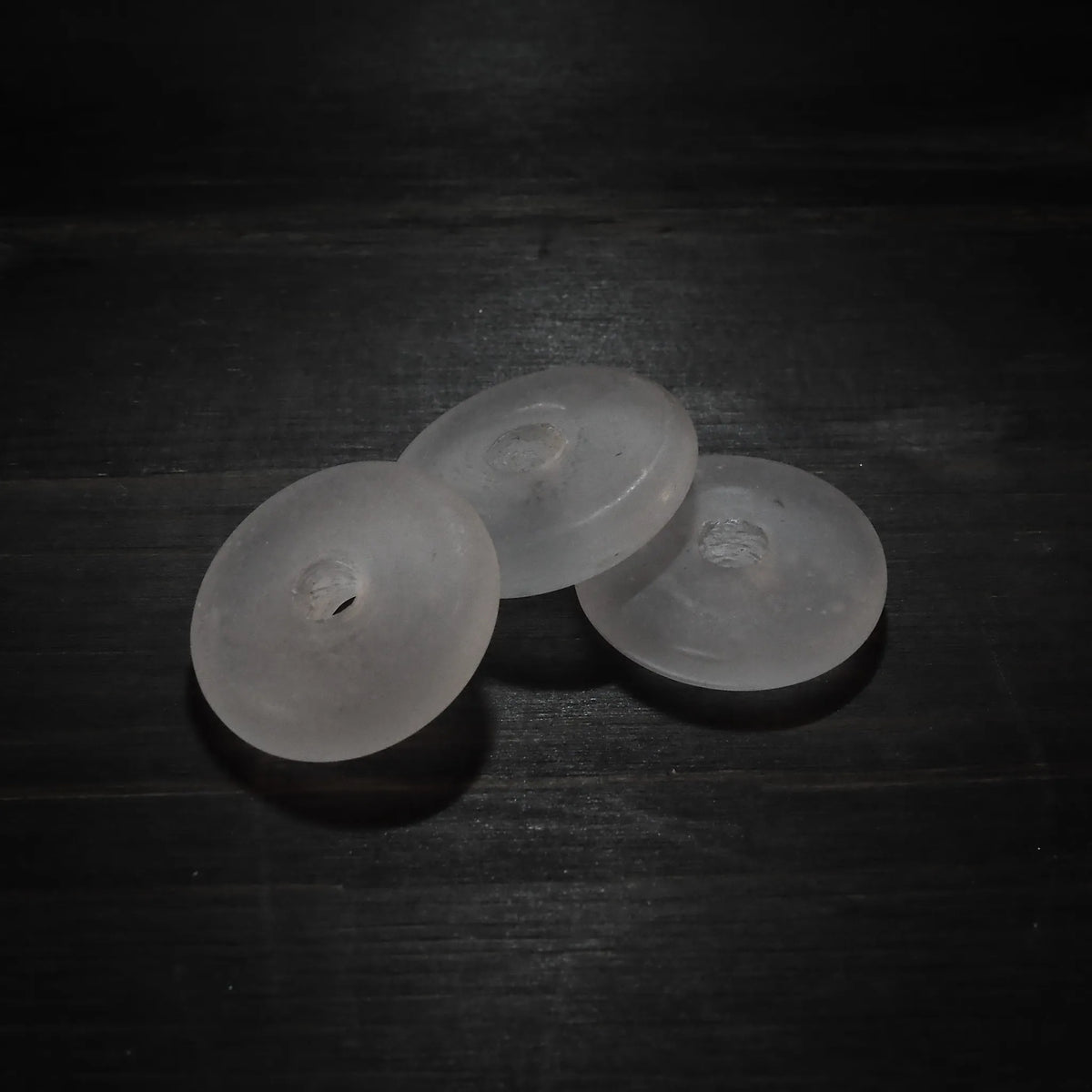 Genomskinliga däckformade glaspärlor i klassisk design, visar form och borrhål från annan vinkel