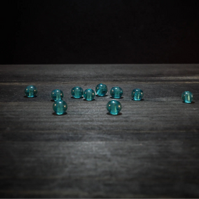 Tio små turkosglaspärlor med hål på träyta