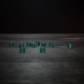 Tio små turkosglaspärlor med facetterad struktur på träyta