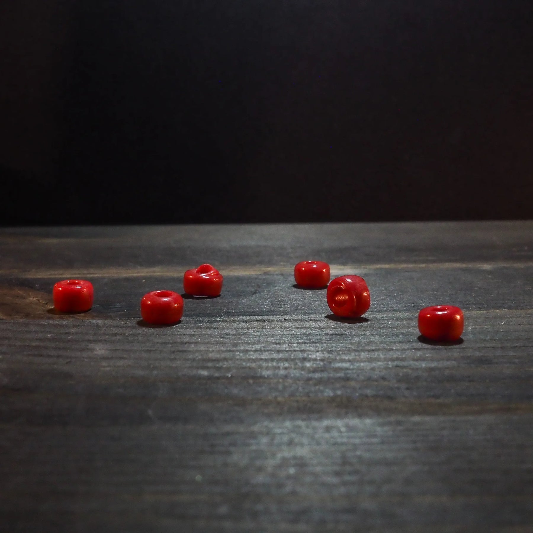 Red glass bead 5mm diameter, glossy finish, spherical shape, shown at actual size for reference