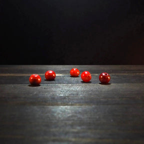 Rund röd glaspärla - Round red glass beads (6mm) on dark wood. Deep translucent ruby-red glass beads ideal for jewelry and craft beading projects.