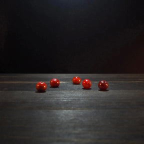 Fem röda glaspärlor på träyta