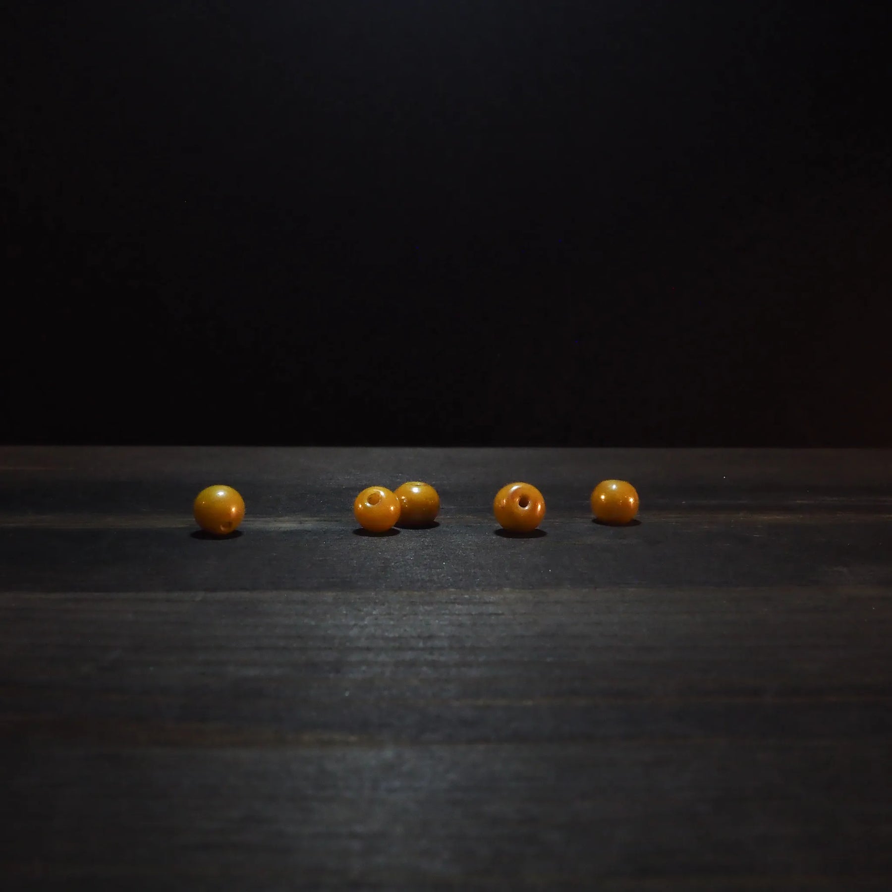 Golden yellow round glass beads, 6mm diameter, displaying polished finish and drilled holes for jewelry making