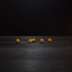 Golden yellow round glass beads, 6mm diameter, displaying polished finish and drilled holes for jewelry making