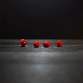 Fyra röda ovalglaspärlor, 7x10mm, på träyta