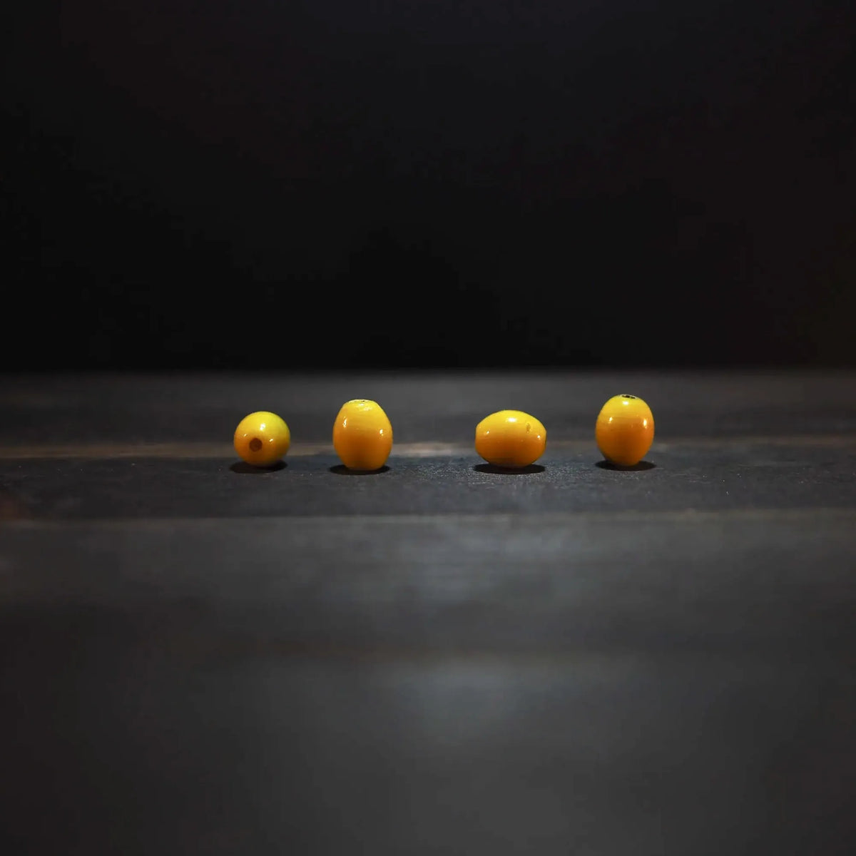 Fyra gula ovalglaspärlor, 7x10mm, på ljus bakgrund