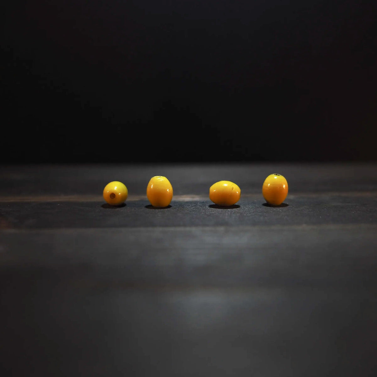 Fyra gula ovalglaspärlor, 7x10mm, på ljus bakgrund