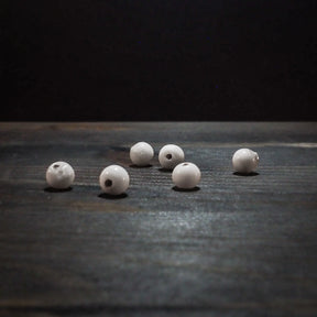 Sex vita glaspärlor, runda och cirka 6mm med genomgående hål, fotograferade på vit bakgrund för tydlig produktöversikt