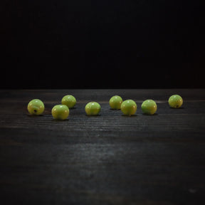 Åtta ljusgröna runda glaspärlor med glansig polerad yta arrangerade på mörkt trä