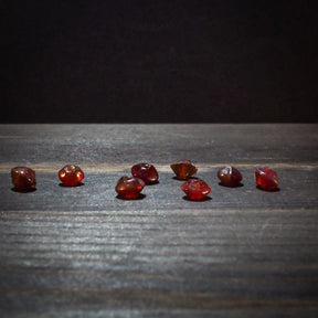 Kantig röd glaspärla med facetterad design på träyta. Visar pärlans lyxiga röda färg, kantiga facetter och högkvalitativt handverk. Perfekt för smyckemaking.