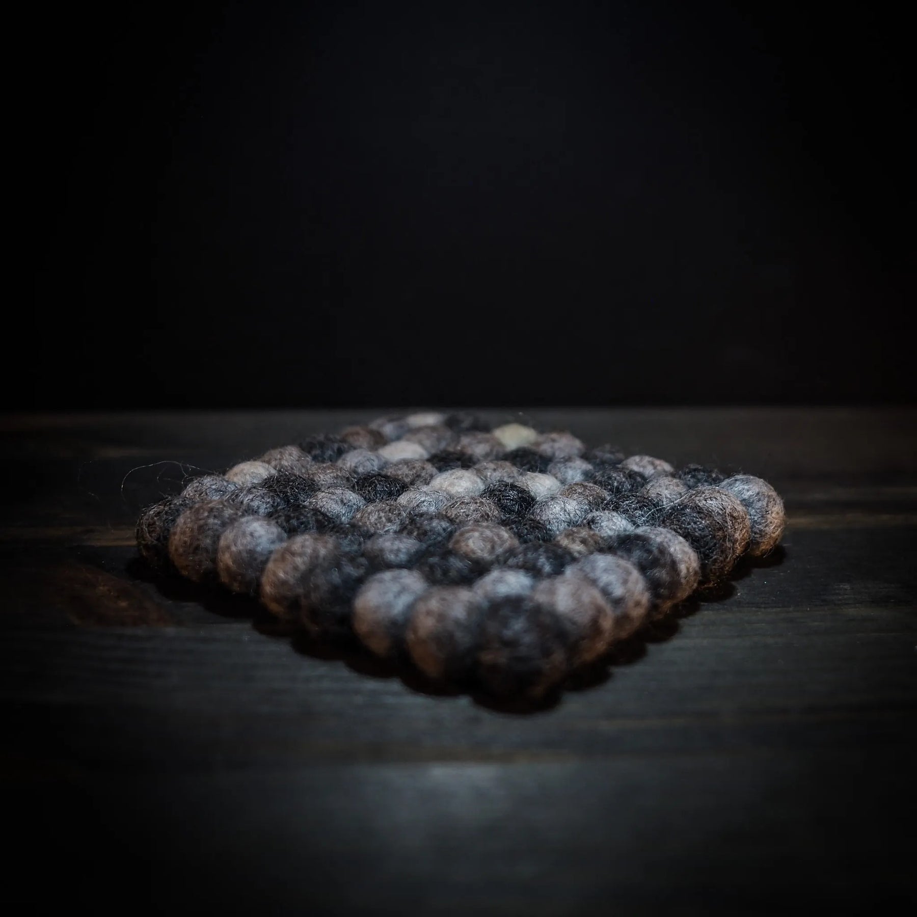 Kvadratiskt filtrat ullunderlägg med färgade ullkulor i geometriskt mönster