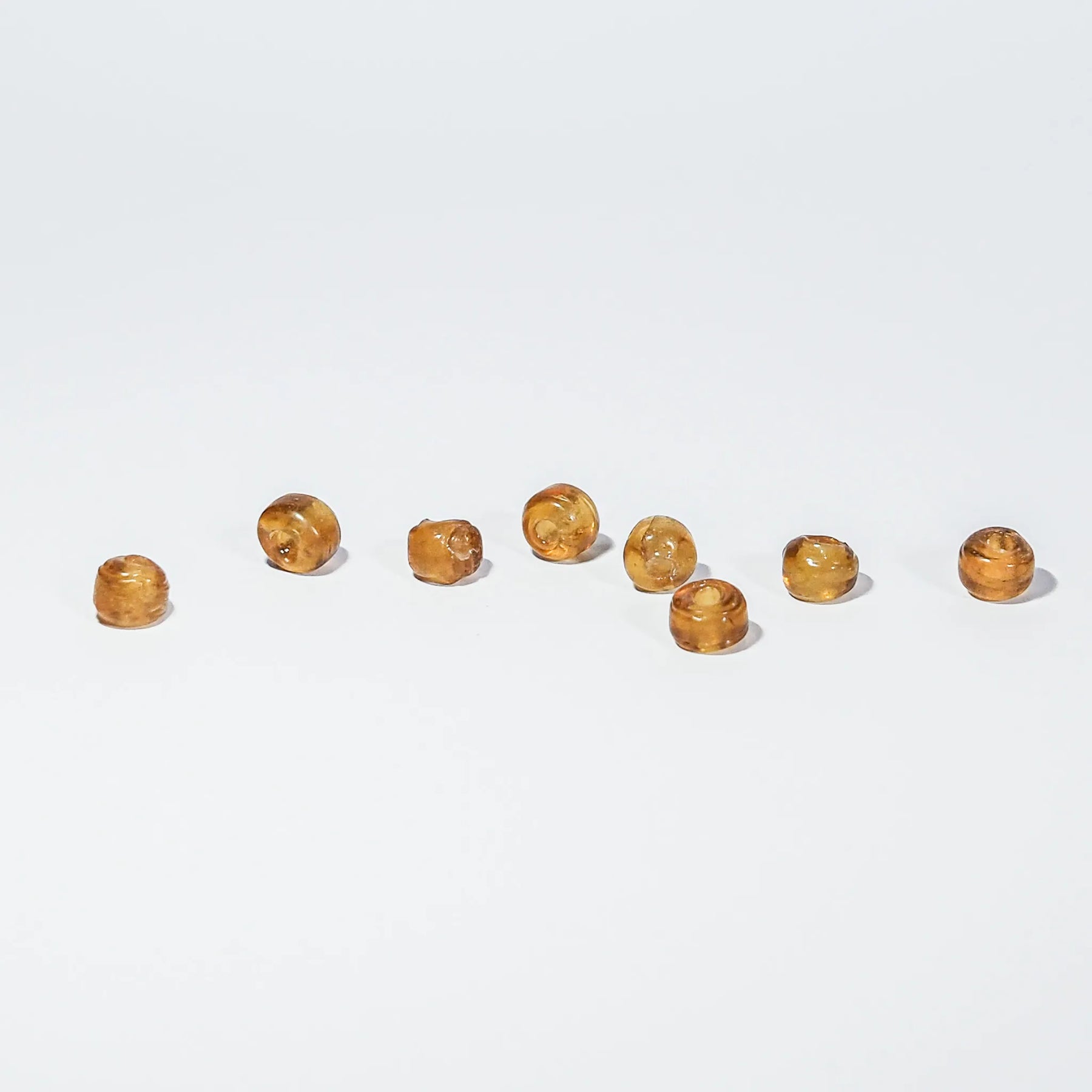 Rund orange glaspärla - Round orange glass beads (5mm) on light background. Warm amber translucent spheres for jewelry crafting and beading projects.