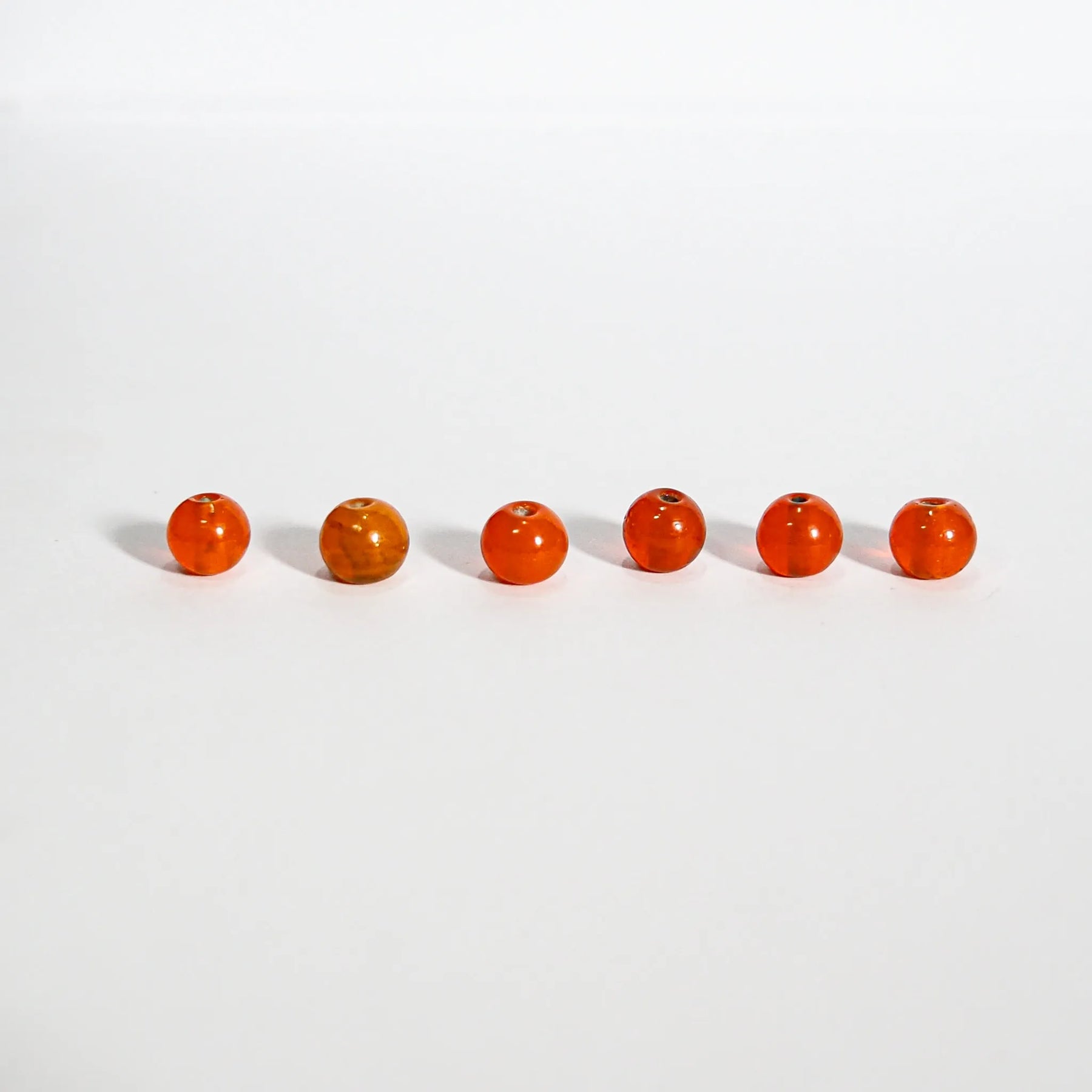 Runda orangeglas pärlor, 6mm, på ljus bakgrund