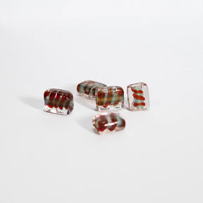 Angular red spiral bead in glass, shown on neutral white background to highlight the bead's faceted shape and red spiral detail. Perfect for jewelry making.