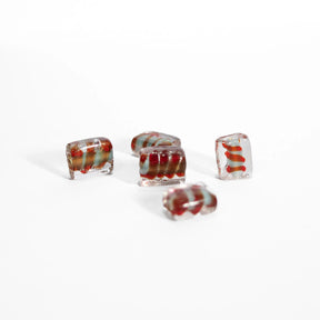 Angular glass bead with red spiral, shown on white background to show the bead's high-quality faceted cut and red spiral detail from another angle.