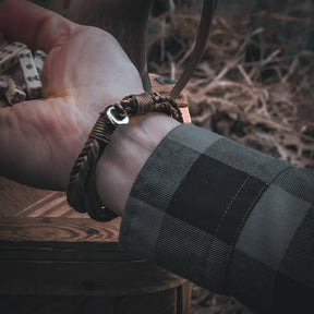 Armband på vrist över trä med nordiska detaljer, närbild på metallklippan