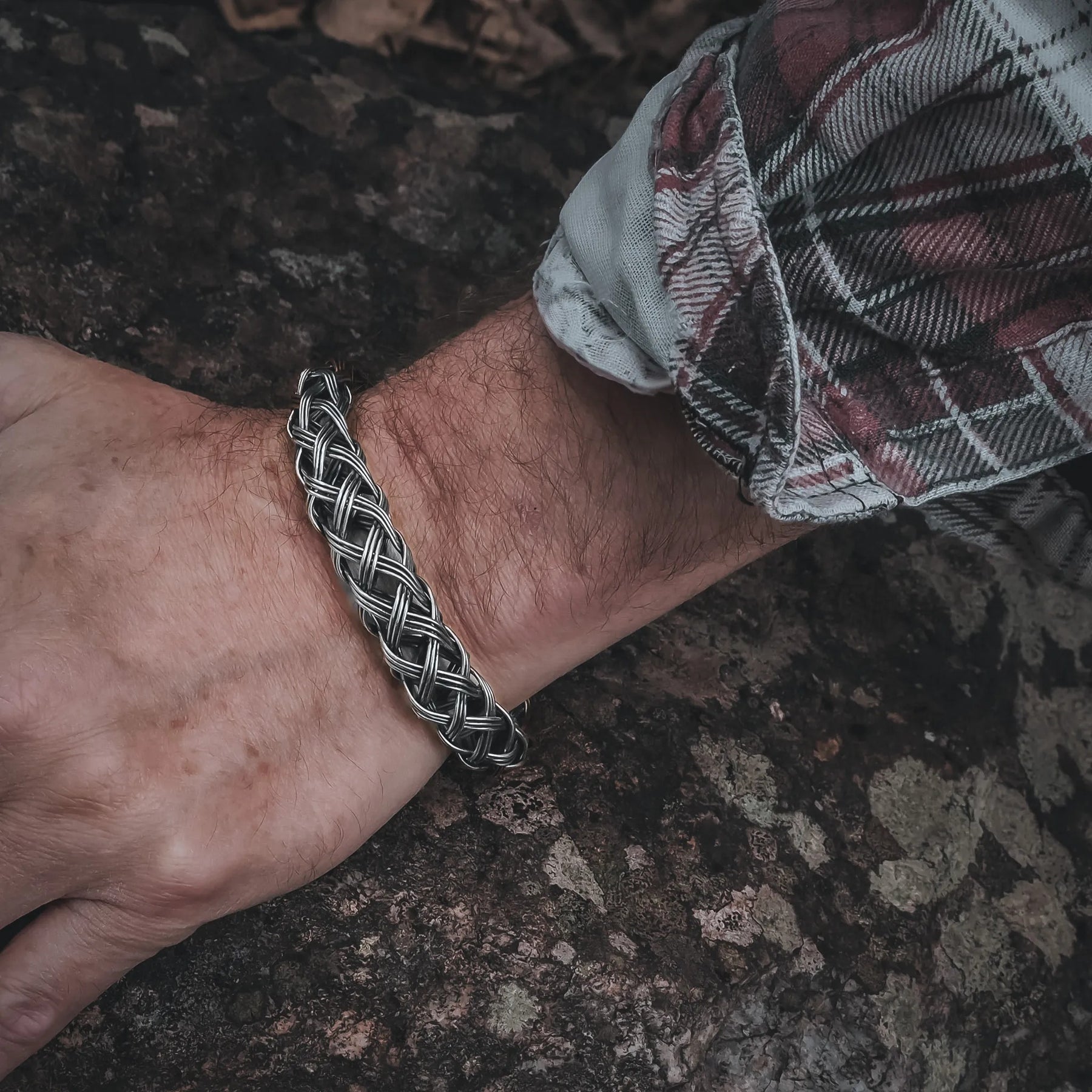 Varga flätat armband på handleden, visar det flätade mönstret i naturligt ljus.