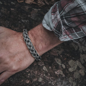 Varga flätat armband på handleden, visar det flätade mönstret i naturligt ljus.