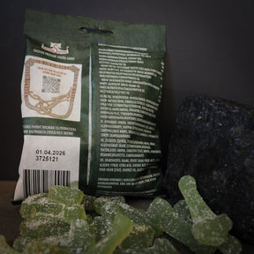 Viking Sweets Iduns syrliga äpplen, förpackning med godisbitar och dekorativa Mjölnirsköldar på mörk bakgrund.