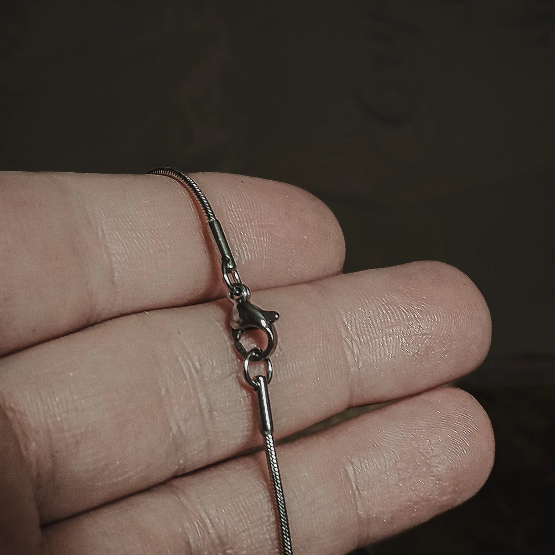 Silverfärgad kirurgisk stålkedja 55cm från artistisk vinkel med synligt lås, visar länkstrukturen i 3D-perspektiv