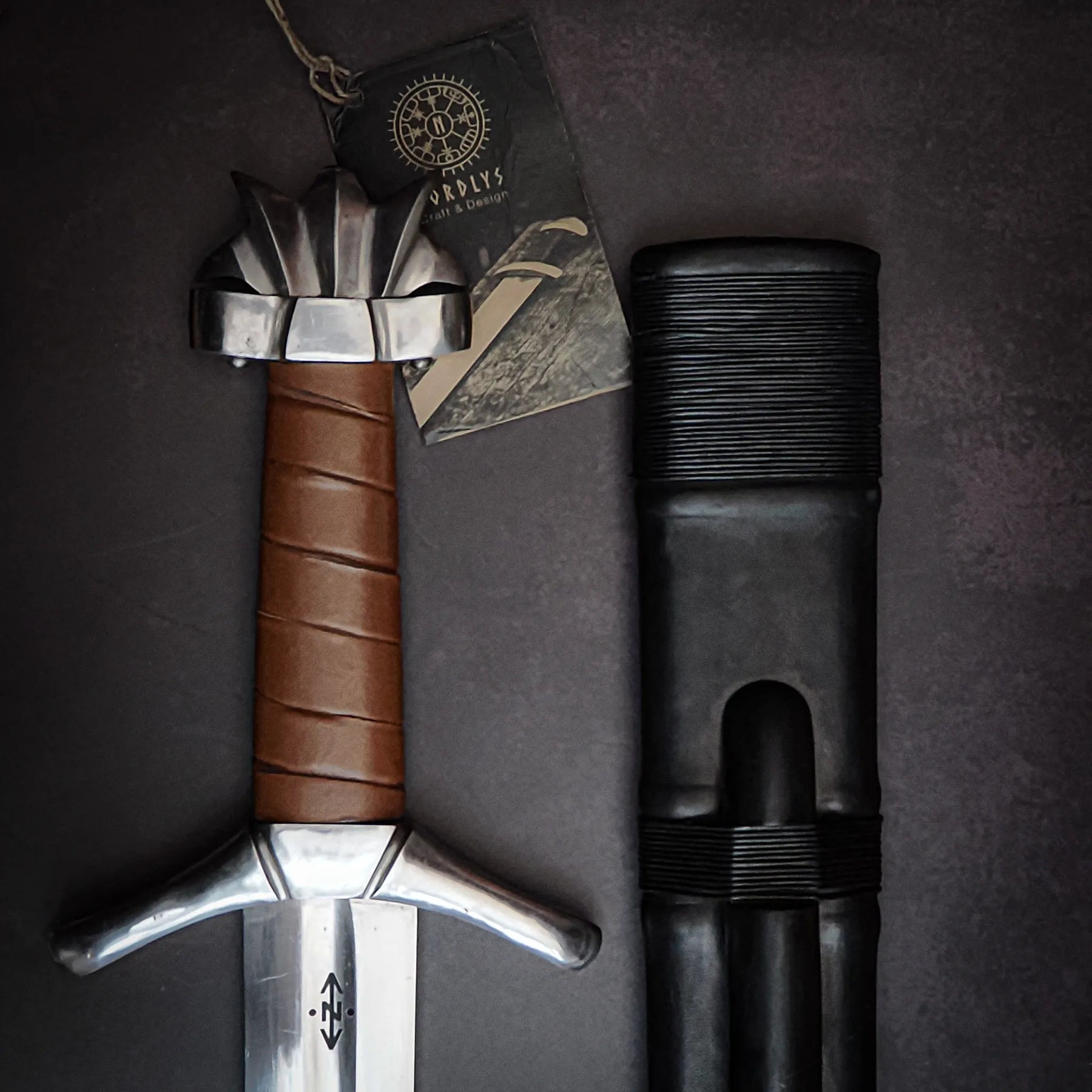 Viking sword product components laid flat: blade, crossguard, leather-wrapped handle, and scabbard. Shows craftsmanship and materials used. Petersens type Z design.