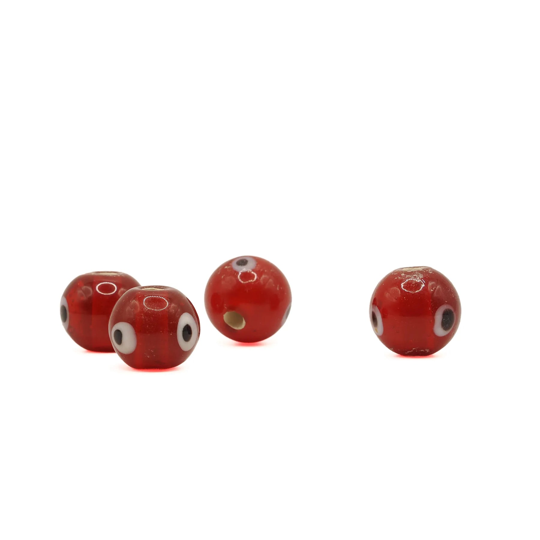 Red glass bead with eye – four beads in a row, eye decoration facing different directions and one hole visible