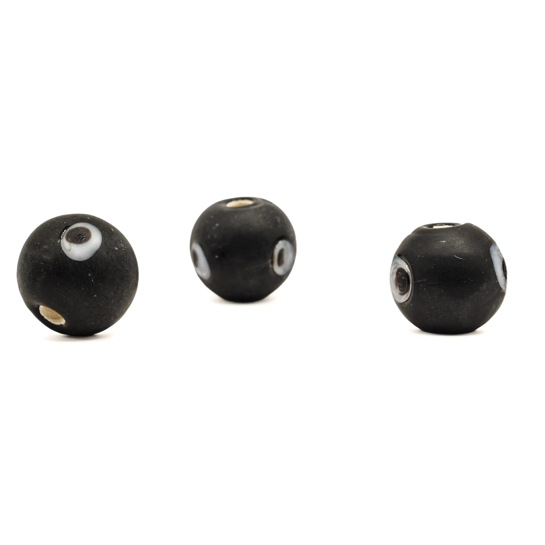 Black glass bead Birka – three beads with eye decoration, one of the holes visible on each bead