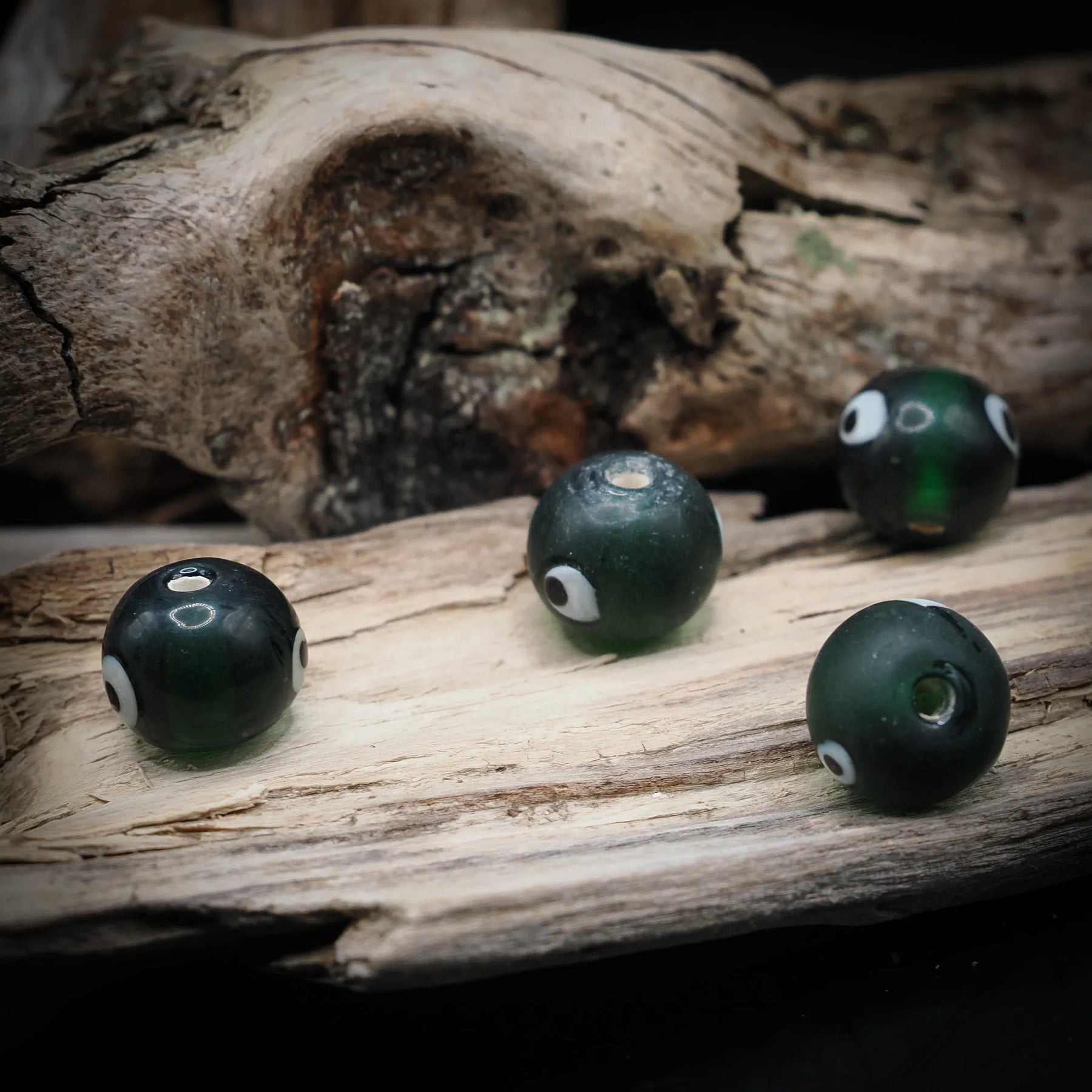 Green glass bead Birka – four beads with white eyes and holes, seen from different angles