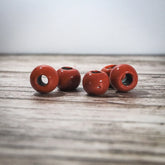 Fyra röda glaspärlor med glansig yta på trä, kustnatur bakgrund
