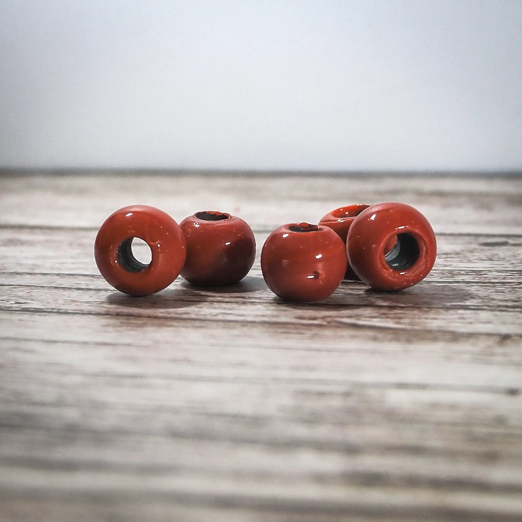 Fyra röda glaspärlor med glansig yta på trä, kustnatur bakgrund